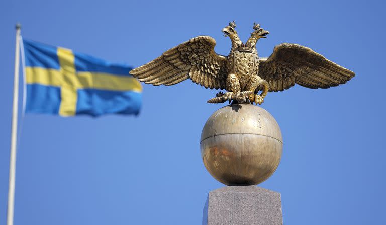 En la Plaza del Mercado de Helsinki, una bandera de Suecia flamea junto a un águila bicéfala, símbolo de la Rusia Imperial. El monumento se erigió en 1835 para conmemorar la primera visita de la emperatriz Alexandra, 26 años después del triunfo del Imperio Ruso sobre el Reino de Suecia.