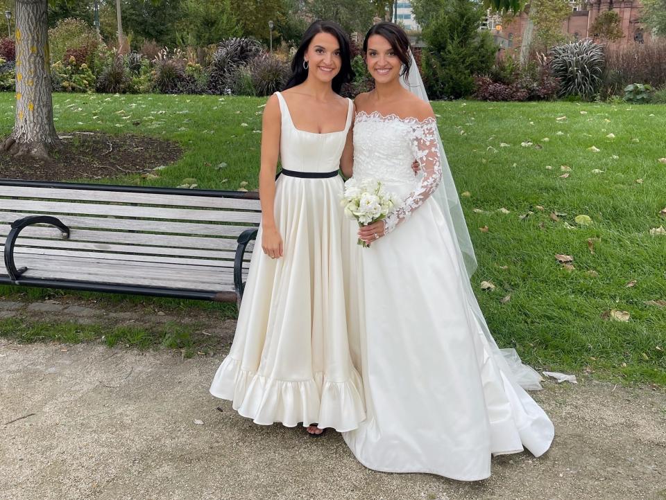 Two women in wedding dresses stand together.