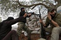 A rebel fighter from 'Jaysh al-Sunna' fires his weapon as his fellow fighter covers his ear during what they said was an offensive to take control of al-Mastouma military camp, which is controlled by forces loyal to Syria's President Bashar al-Assad, beside Idlib city May 12, 2015. REUTERS/Khalil Ashawi