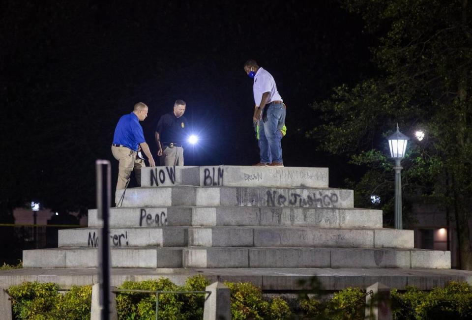 People inspect the platform where the 75-foot Confederate monument on the North Carolina Capitol grounds once stood for 125 years honoring the “bravery of the Southern soldier” in the Civil War, on Wednesday night, Jun. 23, 2020, in Raleigh, N.C. Gov. Roy Cooper ordered its removal, along with two other Confederate monuments, the day after protesters pulled down two bronze soldiers that stood midway on the monumentÕs base and law enforcement officers were injured.