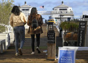 Signs are seen asking people to keep their distance from each other as two women walk on the Malibu Pier Monday, March 23, 2020, in Malibu, Calif. Officials are trying to dissuade people from using the beaches after California Gov. Gavin Newsom ordered the state's 40 million residents to stay at home indefinitely. His order restricts non-essential movements to control the spread of the coronavirus that threatens to overwhelm the state's medical system. (AP Photo/Mark J. Terrill)