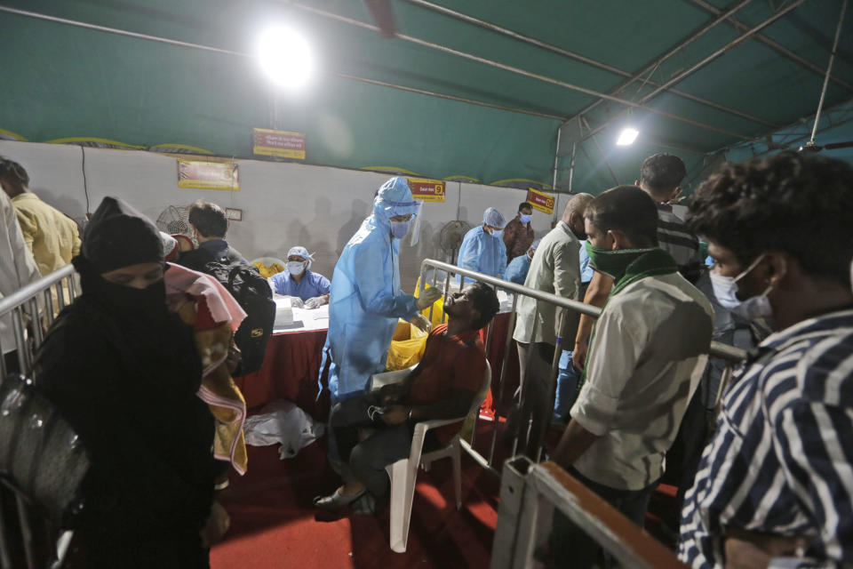 A health worker takes a nasal swab sample of a passenger to test for COVID-19 at a facility erected at a railway station to screen people coming from outside the city, in Ahmedabad, India, Friday, Sept. 18, 2020. India's coronavirus cases jumped by another 96,424 in the past 24 hours, showing little sign of leveling. India is expected to have the highest number of confirmed cases within weeks, surpassing the United States, where more than 6.67 million people have been infected. (AP Photo/Ajit Solanki)