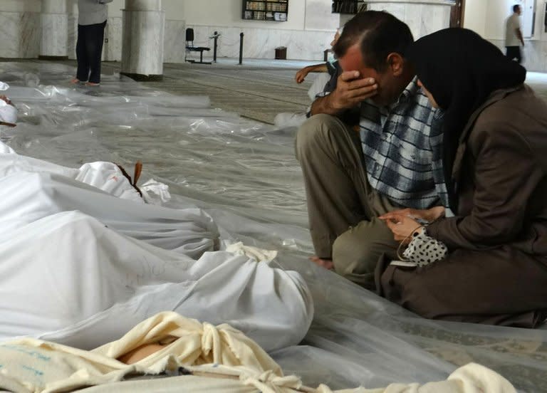 A Syrian couple mourn in front of bodies wrapped in shrouds after what rebels said was a toxic gas attack in Ghouta, on the outskirts of Damascus, on August 21, 2013, in a handout image released by the Syrian opposition's Shaam News Network. The regime in war-torn Syria came under intense pressure Thursday to allow UN inspectors to probe an alleged chemical weapons attack near Damascus