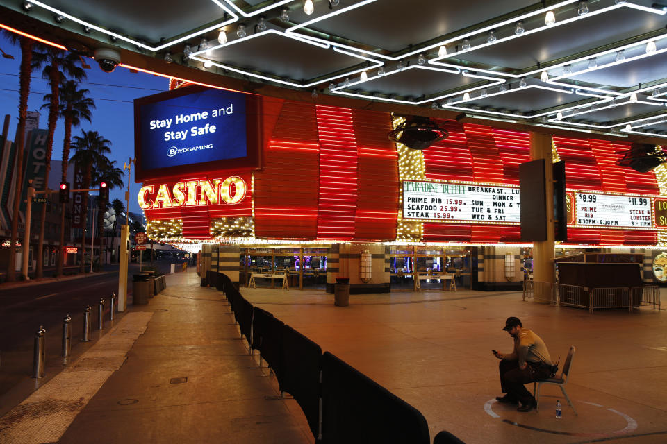 In this April 19, 2020, photo, a lone security guard watches over casinos shuttered due to the coronavirus outbreak in Las Vegas. "For heaven's sake," said Las Vegas mayor Carolyn Goodman at an April city council meeting, "being closed is killing us already, and killing Las Vegas, our industry, our convention and tourism business that we have all worked so hard to build." (AP Photo/John Locher)