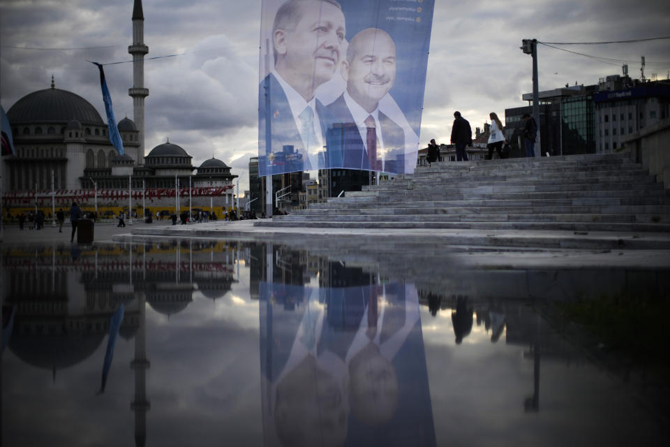 Pedestrians walk past a giant banner of Turkish President and People's Alliance's presidential candidate Recep Tayyip Erdogan, left, at Taksim square in Istanbul, Turkey, Wednesday, May 10, 2023. (AP Photo/Francisco Seco)