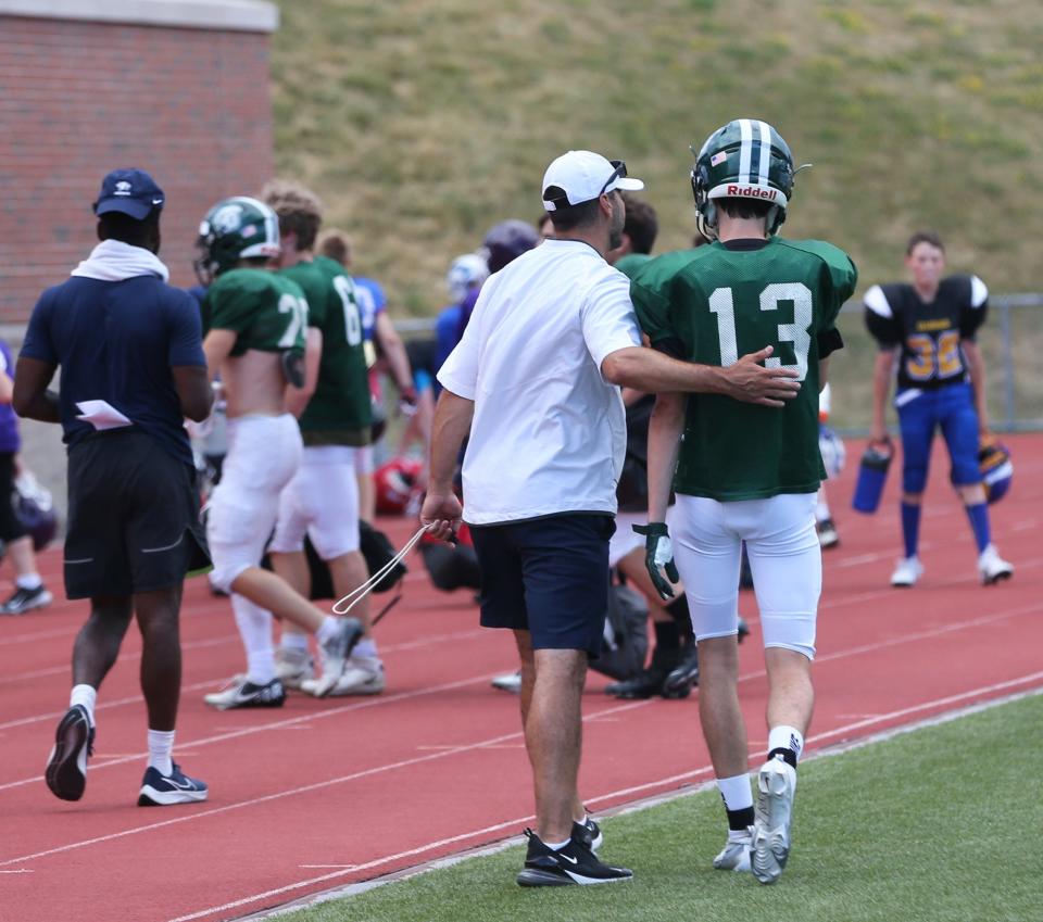 University of New Hampshire head football coach Rick Santos chats with a young player during the program's annual youth football camp this week in Durham.