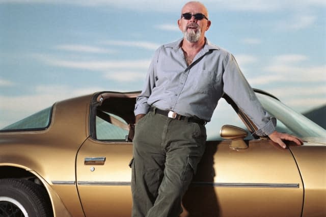 Mature man leaning against sports car, portrait