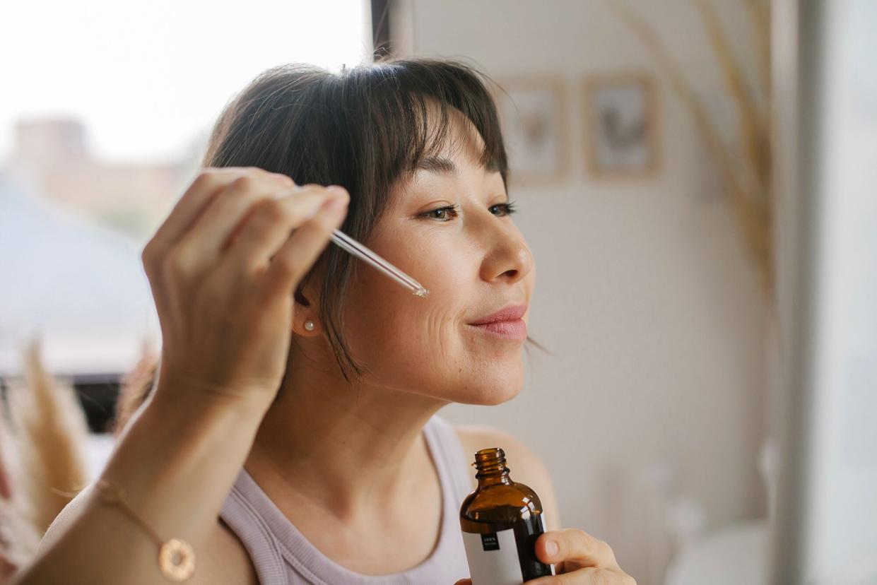 woman applying serum to face with dropper