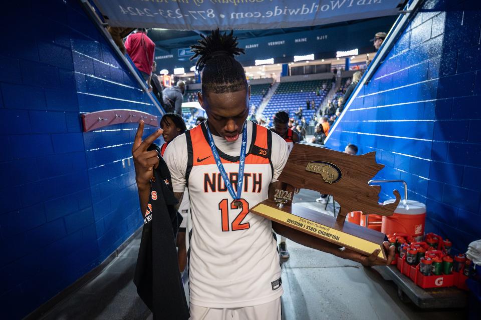 North captain Joe Okla carries the state championship trophy to the locker room after the Polar Bears defeated Franklin, 59-53, to win the D1 basketball state championship at the Tsongas Center in Lowell on Sunday.