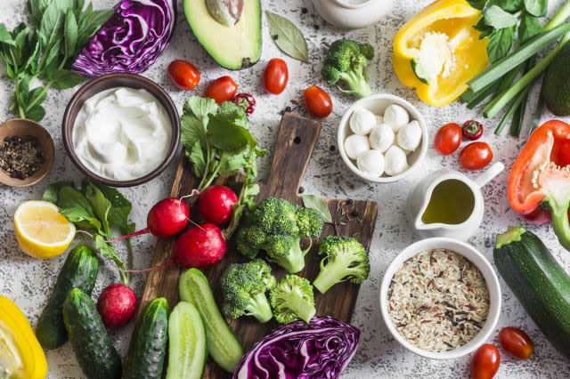 Balanced healthy diet food background in a Mediterranean style. Fresh vegetables, wild rice, fresh yogurt and goat cheese on a light background, top view. Flat lay