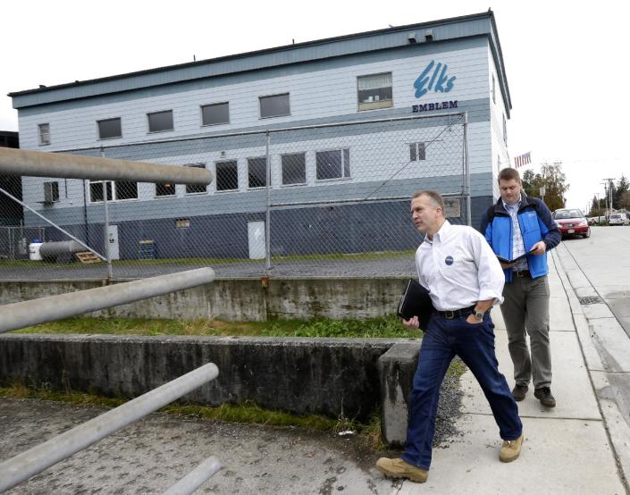 In this Oct. 10, 2014 photo, Republican Dan Sullivan, left, walks near the Petersburg Elks Lodge Hall after stopping at a luncheon where Alaska Gov. Sean Parnell was speaking in Petersburg, Alaska. The Republican, and former state attorney general, is challenging U.S. Sen. Dan Begich for his seat in the hotly contested race that some analysts say could tip the party balance of the U.S. Senate. At right, spokesman Mike Anderson checks the candidate&#39;s schedule and list of commitments for the rest of the day. (AP Photo/Ted S. Warren)