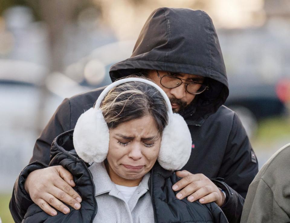 A man puts his arms on a woman as she cries