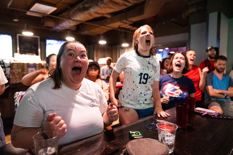 An enthusiastic crowd, mostly of women in T-shirts, shriek with delight.