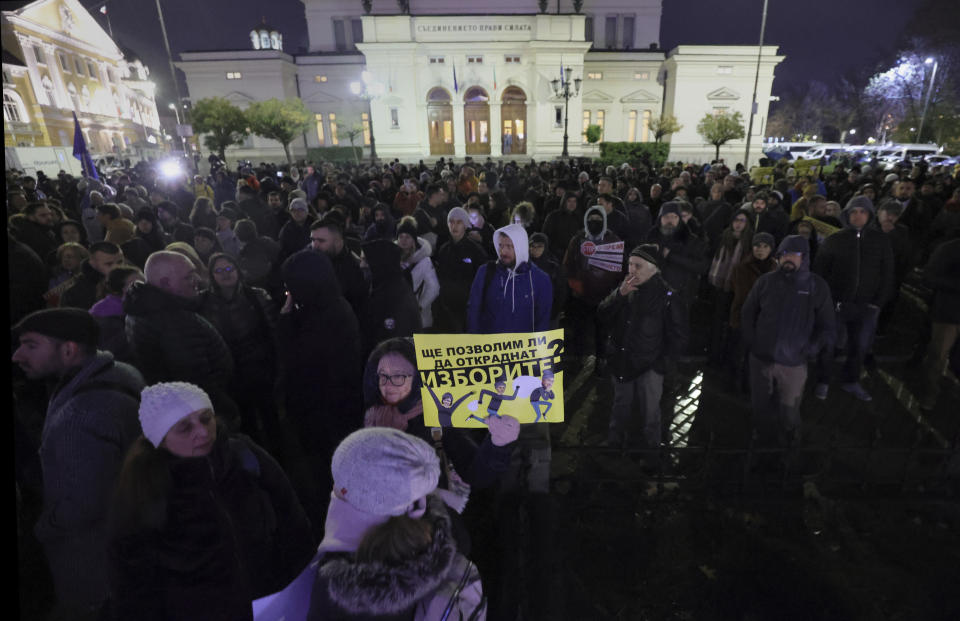 Protesters hold posters that read: "Will we allow them to steal our vote?" as hundreds of Bulgarians gather in front of Bulgarian Parliament on Thursday, Dec. 1, 2022. Hundreds of people attended a street protest in Bulgaria's capital to oppose a revision of the Election Code that reinstates paper ballots, which the previous reformist government had replaced with voting machines. (AP Photo/Valentina Petrova)