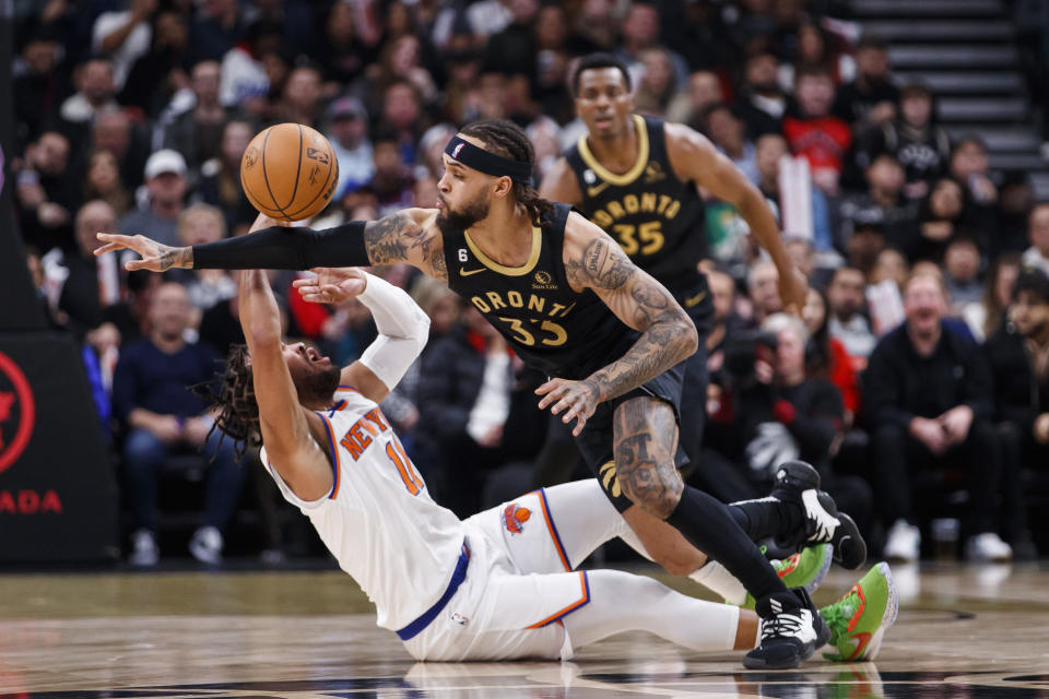 Toronto Raptors guard Gary Trent Jr. (33) and New York Knicks guard Jalen Brunson (11) try to get possession of the ball during the first half of an NBA basketball game Friday, Jan. 6, 2023, in Toronto. (Cole Burston/The Canadian Press via AP)