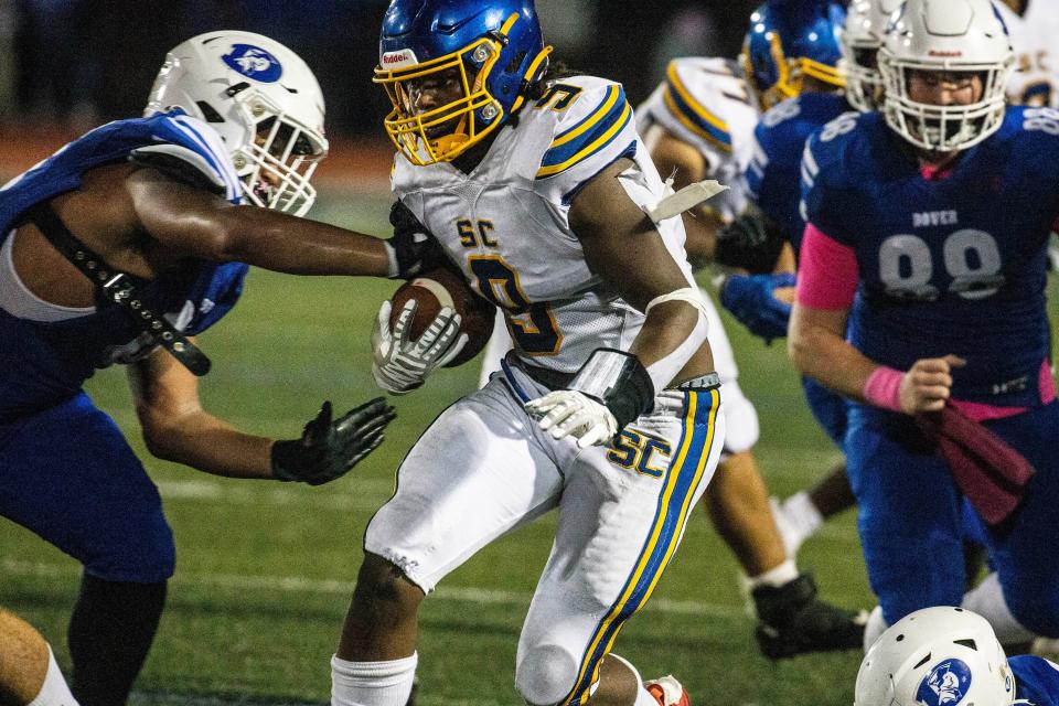 Sussex Central senior Kevon Moore-Briddell (9) hangs on to the ball and braces for the takedown by Dover junior Michael Stevenson (66) during the football game at Dover High, Friday, Oct. 27, 2023. Sussex Central won 13-12.