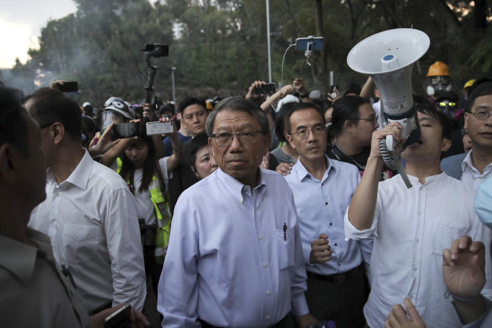 Professor Rocky Tuan, the president of the Chinese University, center, arrives to negotiate with the students and police after a clash on the campus of Chinese University in Hong Kong, Tuesday, Nov. 12, 2019. Police fired tear gas at protesters who littered streets with bricks and disrupted morning commutes and lunch breaks Tuesday after an especially violent day in Hong Kong's five months of anti-government demonstrations. (AP Photo/Kin Cheung)