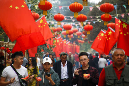 FILE PHOTO: People walk under Chinese national flags in the Old City in Kashgar in Xinjiang Uighur Autonomous Region, China September 6, 2018. REUTERS/Thomas Peter/File Photo