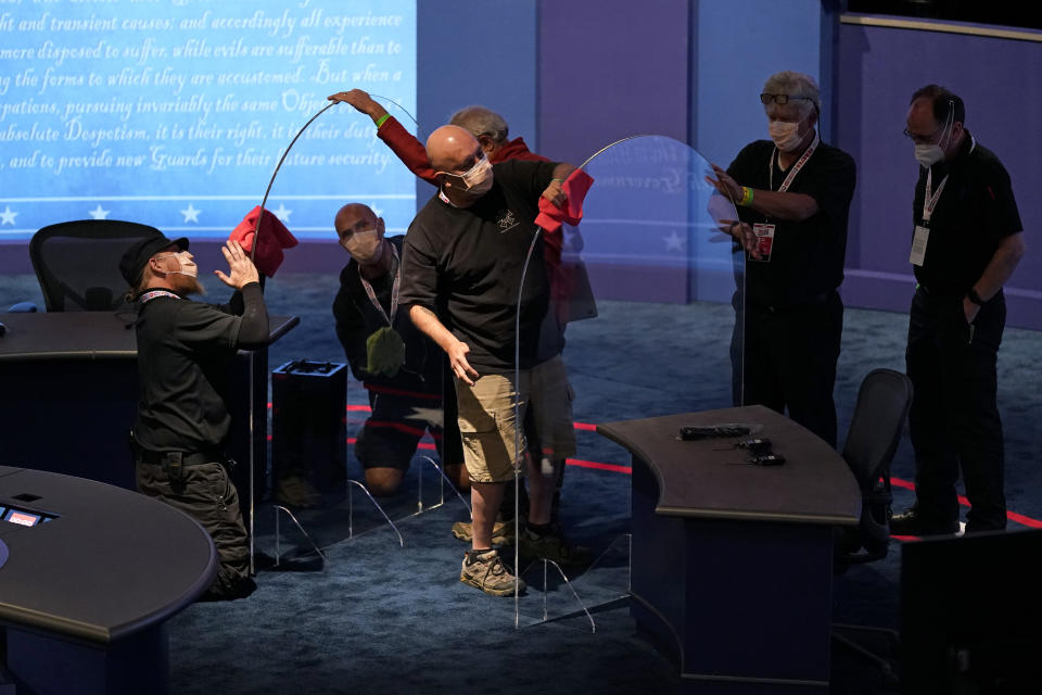 Workers clean protective plastic panels onstage between tables for Vice President Mike Pence and Democratic vice presidential candidate, Sen. Kamala Harris, D-Calif., as preparations take place for the vice presidential debate in Kingsbury Hall at the University of Utah, Tuesday, Oct. 6, 2020, in Salt Lake City. (AP Photo/Patrick Semansky)