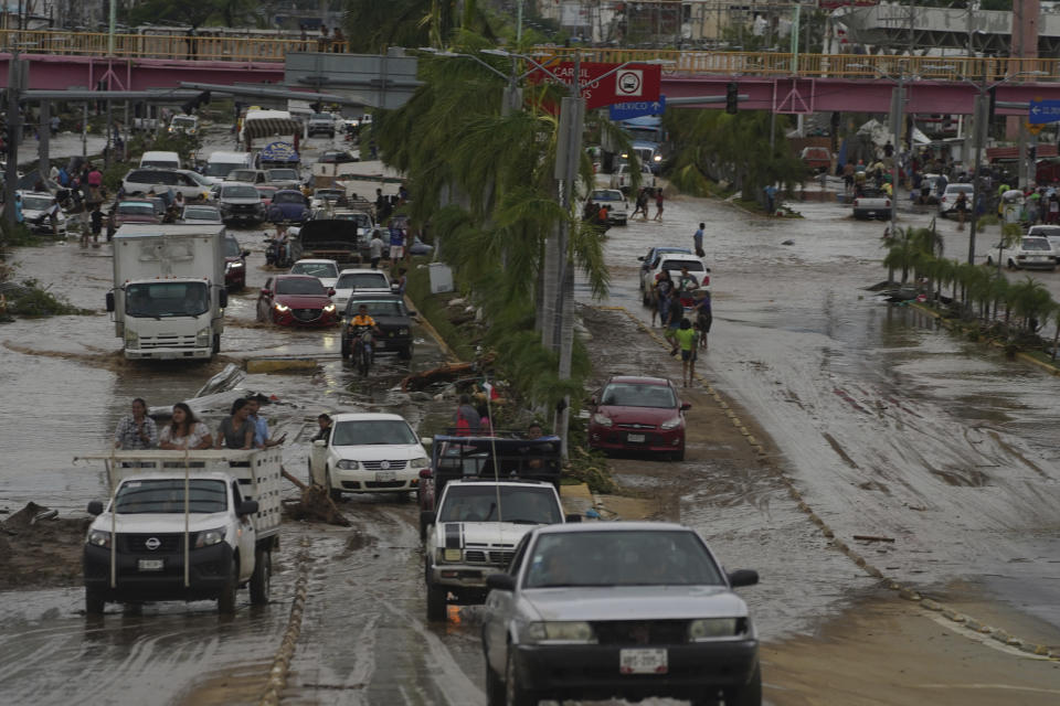 Autos cruzan una avenida anegada tras el paso del huracán Otis por Acapulco, México, el 25 de octubre de 2023. (AP Foto/Marco Ugarte)