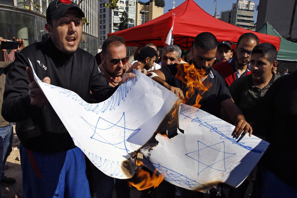 Anti-government protesters burn a poster with the Star of David after riot police open the road, in Beirut, Lebanon, Thursday, Oct. 31, 2019. Army units and riot police took down barriers and tents set up by protesters in the middle of highways and major intersections Thursday. (AP Photo/Bilal Hussein)