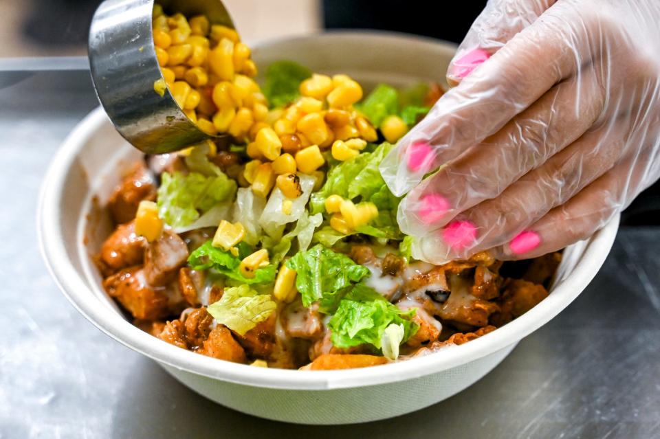 Employee Emmaline Kohuth prepares a chicken bowl for a customer at Grand Grillin on Tuesday, June 13, 2023, in East Lansing.