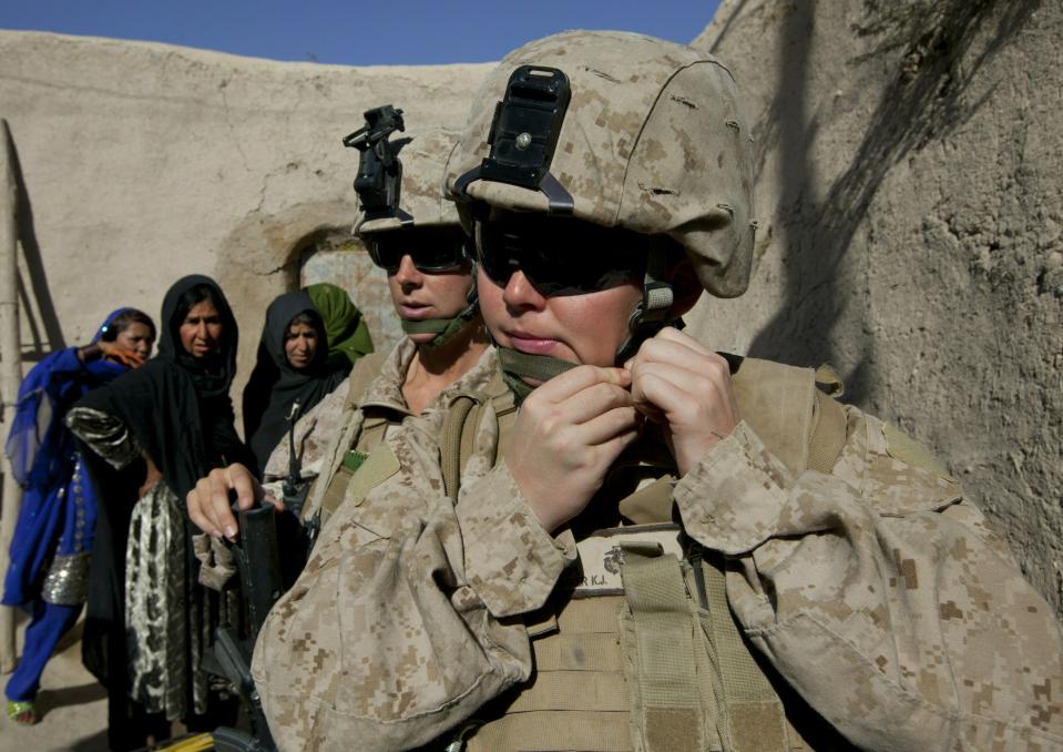 MUSA QALA, AFGHANISTAN - NOVEMBER 21: (SPAIN OUT, FRANCE OUT, AFP OUT) Lance Corporal Kristi Baker, 21, (R) and Sargent Sheena Adams (L), 25, US Marines with the FET (Female Engagement Team) 1st Battalion 8th Marines, Regimental Combat team II put on their helmets as they leave a compound after visiting Afghan women on November 21, 2010 in Musa Qala, Afghanistan. There are 48 women presently working along the volatile front lines of the war in Afghanistan deployed as the second Female Engagement team participating in a more active role, gaining access where men can't. The women, many who volunteer for the 6.5 month deployment take a 10 week course at Camp Pendleton in California where they are trained for any possible situation, including learning Afghan customs and basic Pashtun language. (Photo by Paula Bronstein/Getty Images)