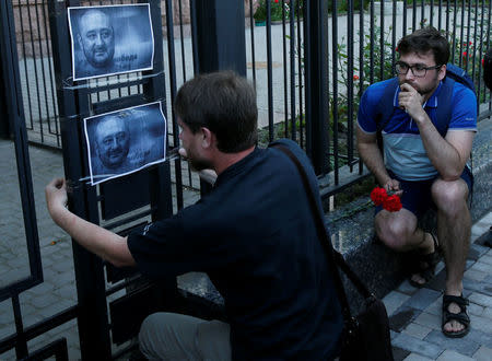 A man hangs a picture of Russian dissident journalist Arkady Babchenko, who was shot dead in the Ukrainian capital on May 29, on a fence of the Russian embassy in Kiev, Ukraine May 30, 2018. REUTERS/Gleb Garanich