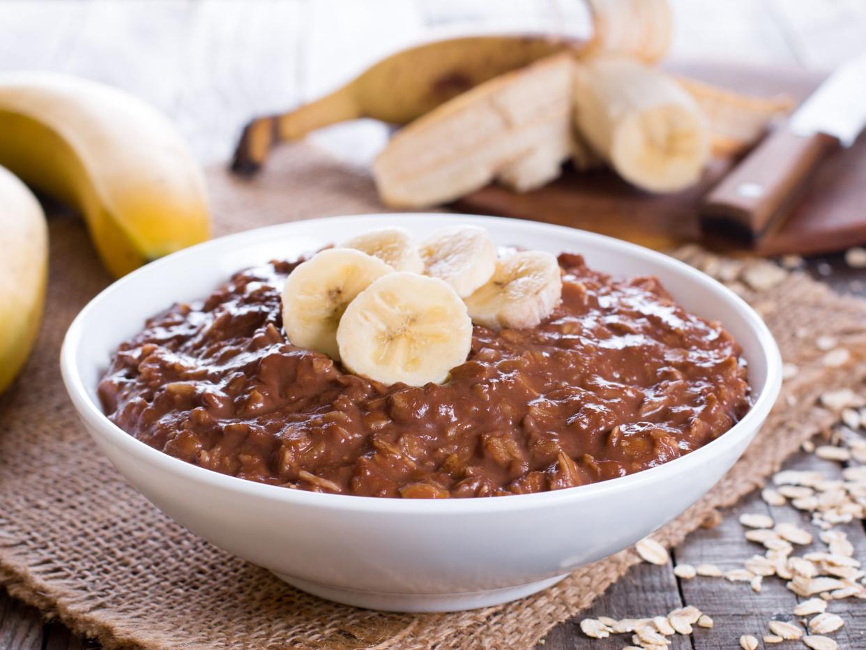 Chocolate oatmeal with banana in white bowl for breakfast, horizontal