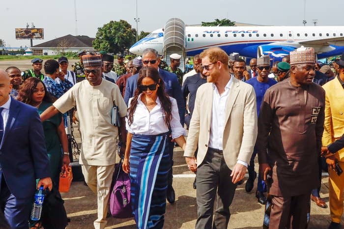 Meghan Markle and Prince Harry walking hand-in-hand as they are escorted from a plane
