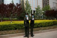 Paramilitary police officers wearing face masks gesture while standing guard on the Changan Avenue in Beijing, as the spread of the novel coronavirus disease (COVID-19) continues