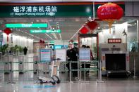 Staff members wearing masks are seen at Pudong International Airport maglev station in Shanghai