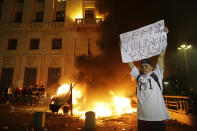 <p> A man holds a banner that reads in Portuguese: "No violence Brazil, peace and love," in front of a burning national television vehicle, set on fire by protestors, in front of City Hall in Sao Paulo, Brazil, Tuesday, June 18, 2013. On Tuesday, thousands of people marched on Sao Paulo’s City Hall building, where a small group fought police in an unsuccessful attempt to force their way in. Some of the biggest demonstrations since the end of Brazil's 1964-85 dictatorship have broke out across this continent-sized country, uniting multitudes frustrated by poor transportation, health services, education and security despite a heavy tax burden. (AP Photo/Nelson Antoine)</p>