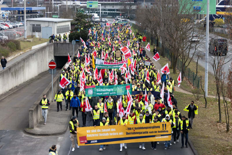 Strikers march from the Lufthansa Aviation Center to Terminal 1 with banners and Verdi flags during a protest.  With renewed warning strikes by several professional groups, the Verdi union is paralyzing important parts of German air traffic on Thursday and Friday. Lando Hass/dpa