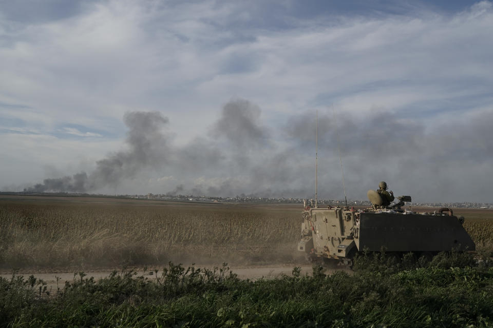 Israeli soldiers patrol as the smoke rises from the Gaza Strip after Israeli strikes on Saturday, Dec. 9, 2023. (AP Photo/Leo Correa)