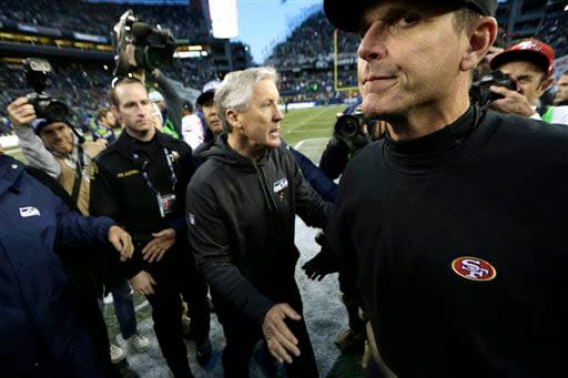 San Francisco 49ers head coach Jim Harbaugh, right, shakes hands with Seattle Seahawks head coach Pete Carroll, center, after an NFL football game, Sunday, Dec. 14, 2014, in Seattle. The Seahawks won 17-7. (AP Photo/John Froschauer)