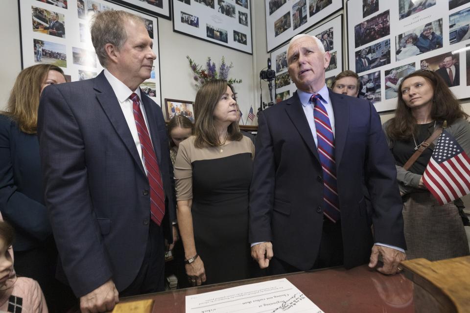 Former Vice President Mike Pence speaks with reporters beside his wife Karen, second from left, and New Hampshire Secretary of State David Scanlan, left, after signing papers to get on the Republican presidential primary ballot at the New Hampshire Statehouse, Friday, Oct. 13, 2023, in Concord, N.H. (AP Photo/Michael Dwyer)