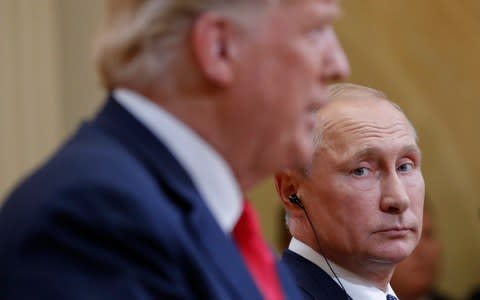 Russian President Vladimir Putin, right, looks over towards President Donald Trump, left, as Trump speaks during their joint news conference at the Presidential Palace in Helsinki - Credit: AP