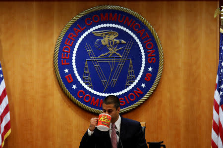 FILE PHOTO: Chairman Ajit Pai drinks coffee ahead of the vote on the repeal of so called net neutrality rules at the Federal Communications Commission in Washington, U.S., December 14, 2017. REUTERS/Aaron P. Bernstein/File Photo