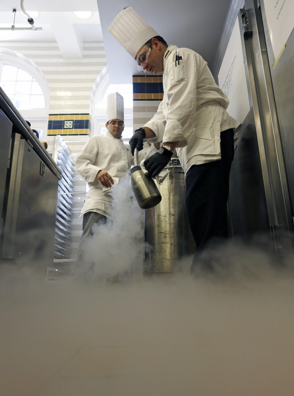 In this image taken on Friday, Sept. 14, 2012, Chef Francisco Migoya, right, fills a container with liquid nitrogen as pastry manager-in-training Douglas Phillips looks on, at the Culinary Institute of America in Hyde Park, N.Y. This esteemed cooking school north of New York City is dramatically pumping up science instruction, saying that tomorrow's chefs will need more technical know-how in the age of molecular gastronomy and sous-vide. (AP Photo/Mike Groll)