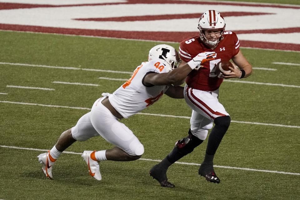 Wisconsin's Graham Mertz tries to run past Illinois's Tarique Barnes during the first half of an NCAA college football game Friday, Oct. 23, 2020, in Madison, Wis. (AP Photo/Morry Gash)