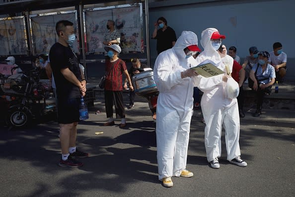 Medical staff members in full protective gear stand outside the Guangan sports centre to assist people who live near or who have visited the Xinfadi Market, a wholesale food market where a new COVID-19 coronavirus cluster has emerged, for testing in Beijing.