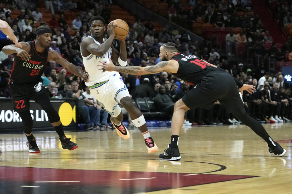 Minnesota Timberwolves guard Anthony Edwards, center, drives to the basket as Miami Heat forward Jimmy Butler (22) and Miami Heat forward Caleb Martin (16) defend during the first half of an NBA basketball game, Monday, Dec. 18, 2023, in Miami. (AP Photo/Lynne Sladky)