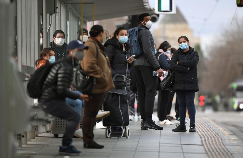 People wearing masks wait for a tram at Melbourne's Flinders Street Station. Source: Getty