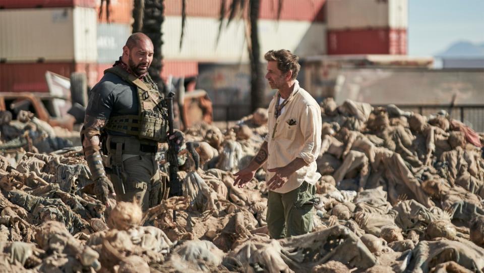 Dave Bautista and Zack Snyder stand among hundreds of zombies in a behind-the-scenes still from Army of the Dead.