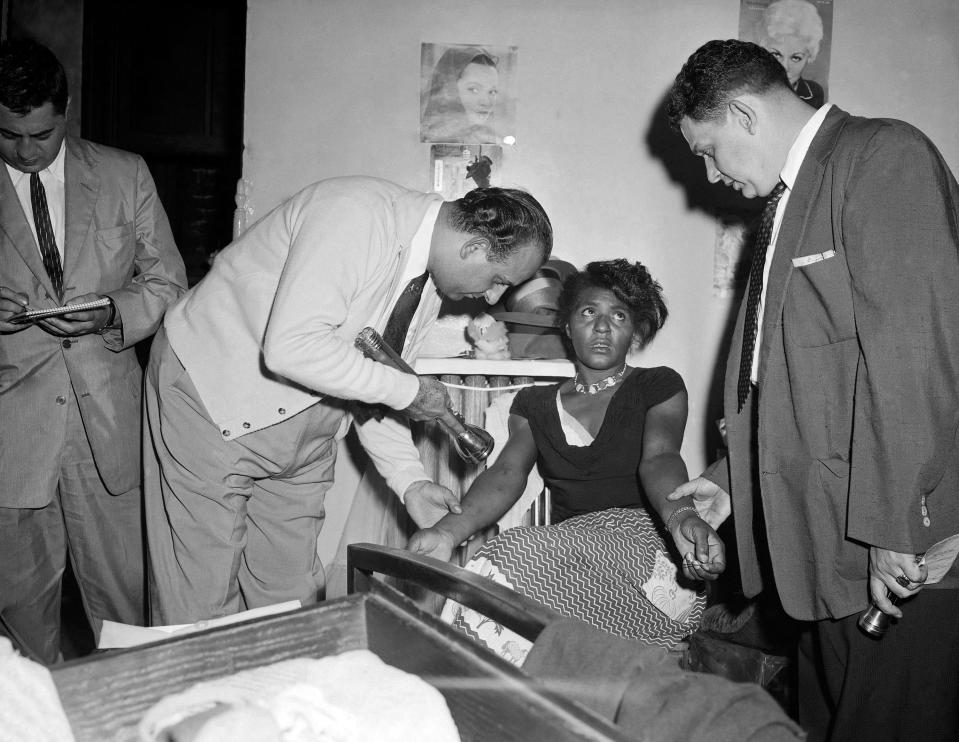 FILE - In this Sept. 22, 1957 file photo, police Detectives John Matassa, center and Sheldon Teller, right, examine the arms of a suspected narcotics addict and dealer in New York. Eric Schneider, a professor at the University of Pennsylvania said after World War II, heroin became a drug primarily used by blacks and Puerto Ricans in the Northeast and by Mexican Americans in the West. In the late 1960s, at the height of the hippie drug experimentation era, there was a resurgence of heroin use among young white people in the East Village and in San Francisco’s Haight-Ashbury district. (AP Photo)