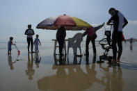 A worker prepares an umbrella for tourists at a beach along the Taiwan Strait in Pingtan, eastern China's Fujian Province, Sunday, Aug. 7, 2022. Taiwan said Saturday that China's military drills appear to simulate an attack on the self-ruled island, after multiple Chinese warships and aircraft crossed the median line of the Taiwan Strait following U.S. House Speaker Nancy Pelosi's visit to Taipei that infuriated Beijing. (AP Photo/Ng Han Guan)