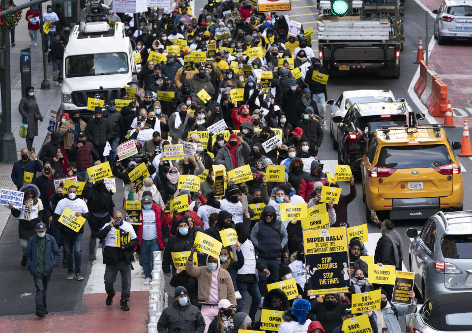 Restaurant and bar owners, employees and union workers march on 42nd Street in support of the restaurant industry, Tuesday, Dec. 15, 202,0 in New York. A ban on indoor dining at New York City restaurants was enacted Monday by officials trying to slow the resurgence of the coronavirus. (AP Photo/Mark Lennihan)