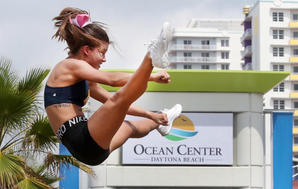 A cheerleader is tossed high in the air as her team practices on the grass around the Ocean Center at the 2022 National Cheerleaders Association and National Dance Alliance Collegiate National Championships in Daytona Beach. The event returns this week with performances April 6-8 at the Bandshell and the Ocean Center.