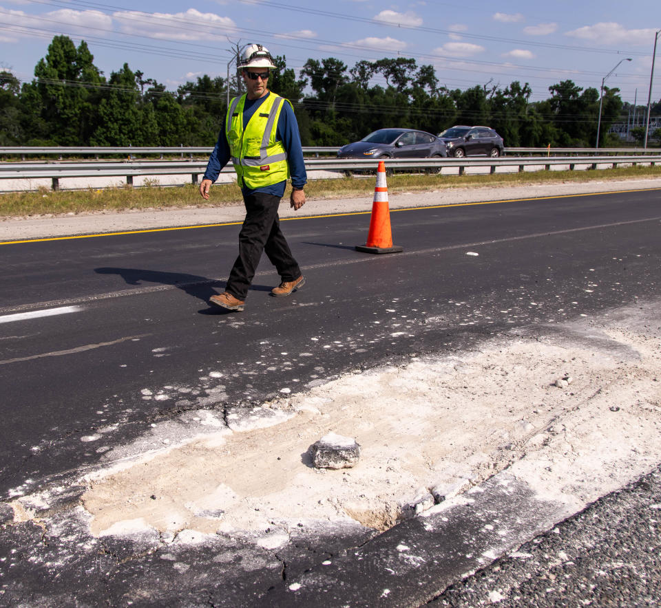 An Anderson Columbia Co. Inc. employee walks by a pothole about 15 feet long, 6 feet wide and more than 3 inches deep, that opened up on Wednesday in the southbound lanes of I-75 near mile marker 349.